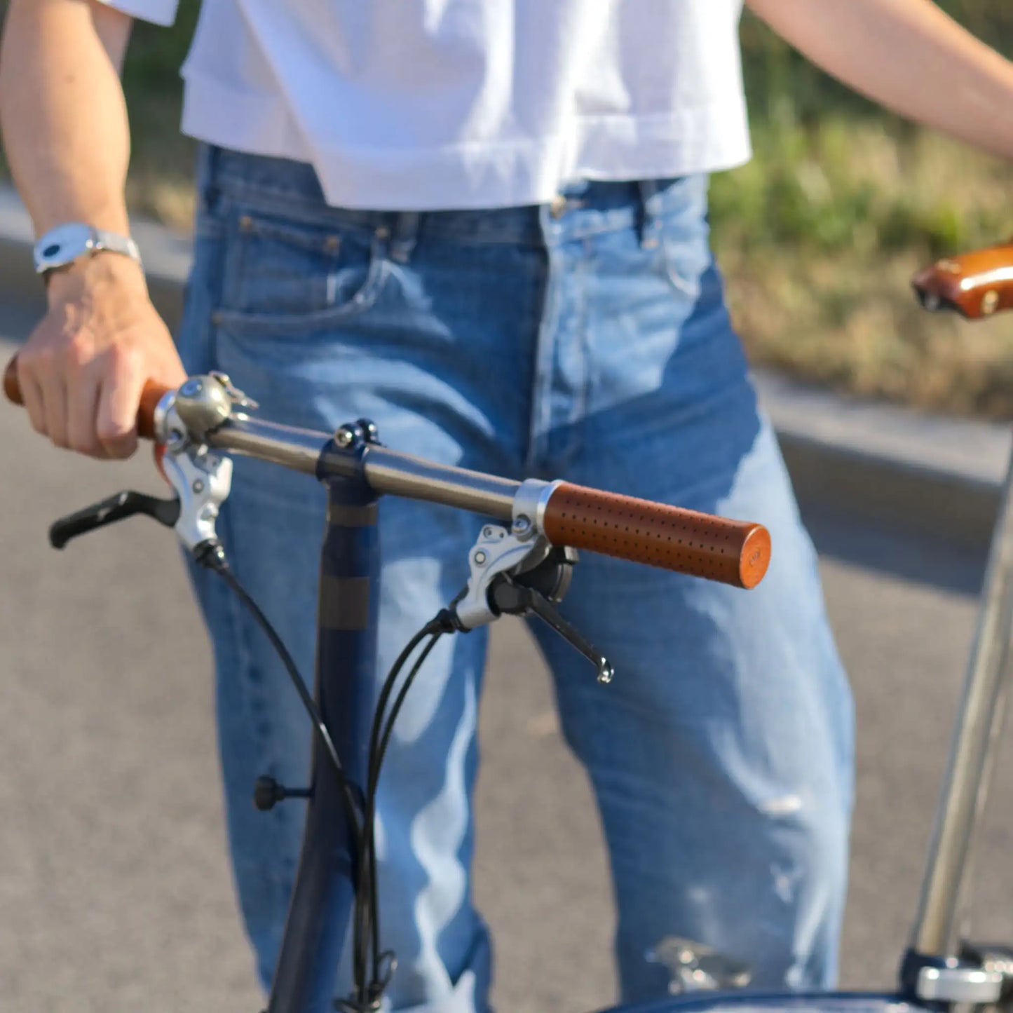 Fahrradgriffe Leder Hellbraun (Honey) mit silbernem Klemmring an einem Brompton Faltrad mit Titanlenker – hochwertige, handgefertigte Ledergriffe für optimalen Grip und Langlebigkeit. Perfekt für anspruchsvolle Brompton-Fahrer, die Wert auf Stil, Komfort und Qualität legen.