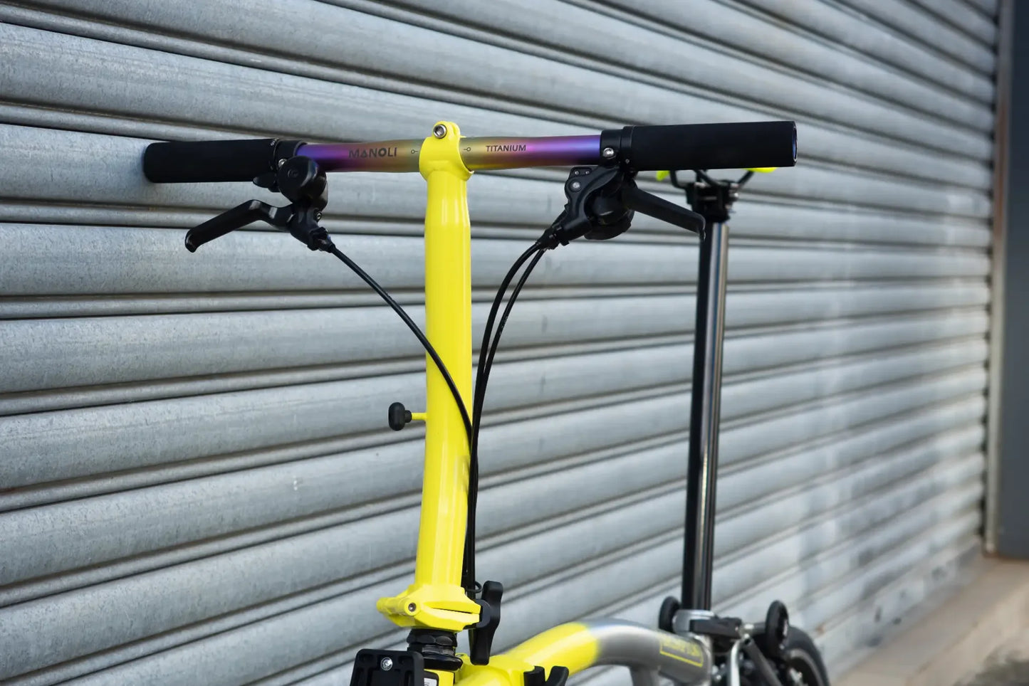 Manoli Titanlenker in der Farbe Rainbow an einem Gelben Brompton Fahrrad