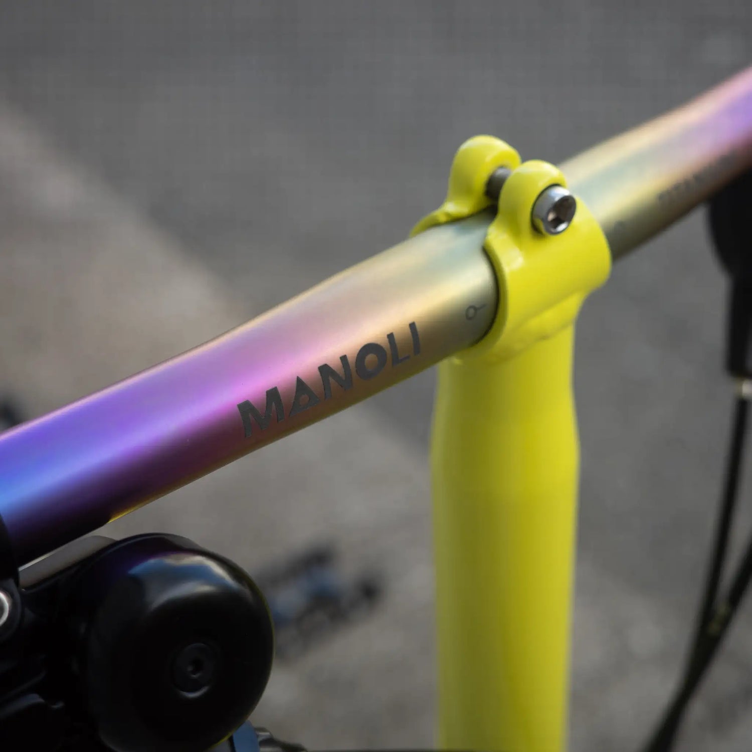 Brompton Faltrad Detailaufnahme Logo in leuchtendem Gelb mit Manoli Titanlenker im einzigartigen Rainbow-Finish – ein stilvolles und individuelles Upgrade für Designliebhaber. Die Kombination aus kräftigem Gelb und schimmerndem Farbverlauf macht dieses Brompton zu einem echten Blickfang.